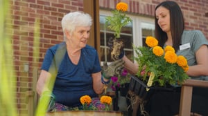 Immanuel employee planting flowers with a senior resident.
