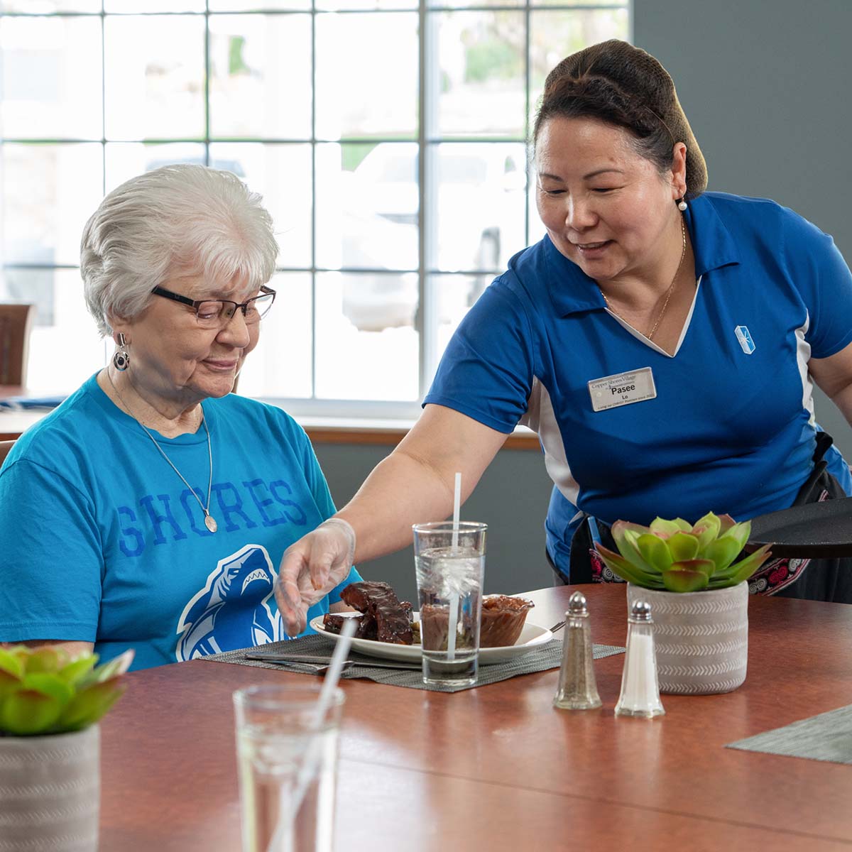 Immanuel server setting down a plate of food for a resident.