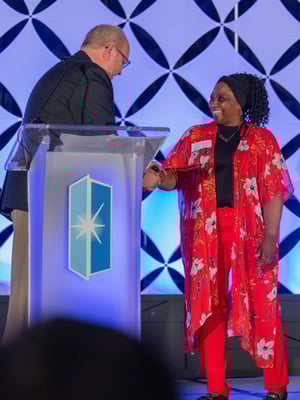 A female Immanuel employee receives an award on stage.