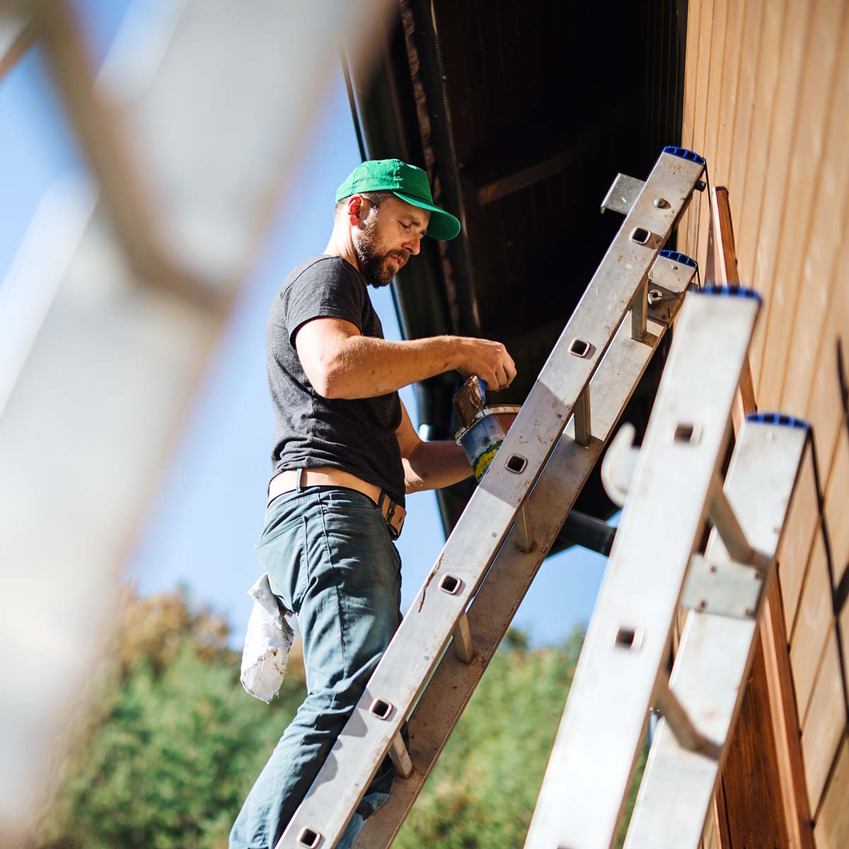 Maintenance worker painting an exterior wall.