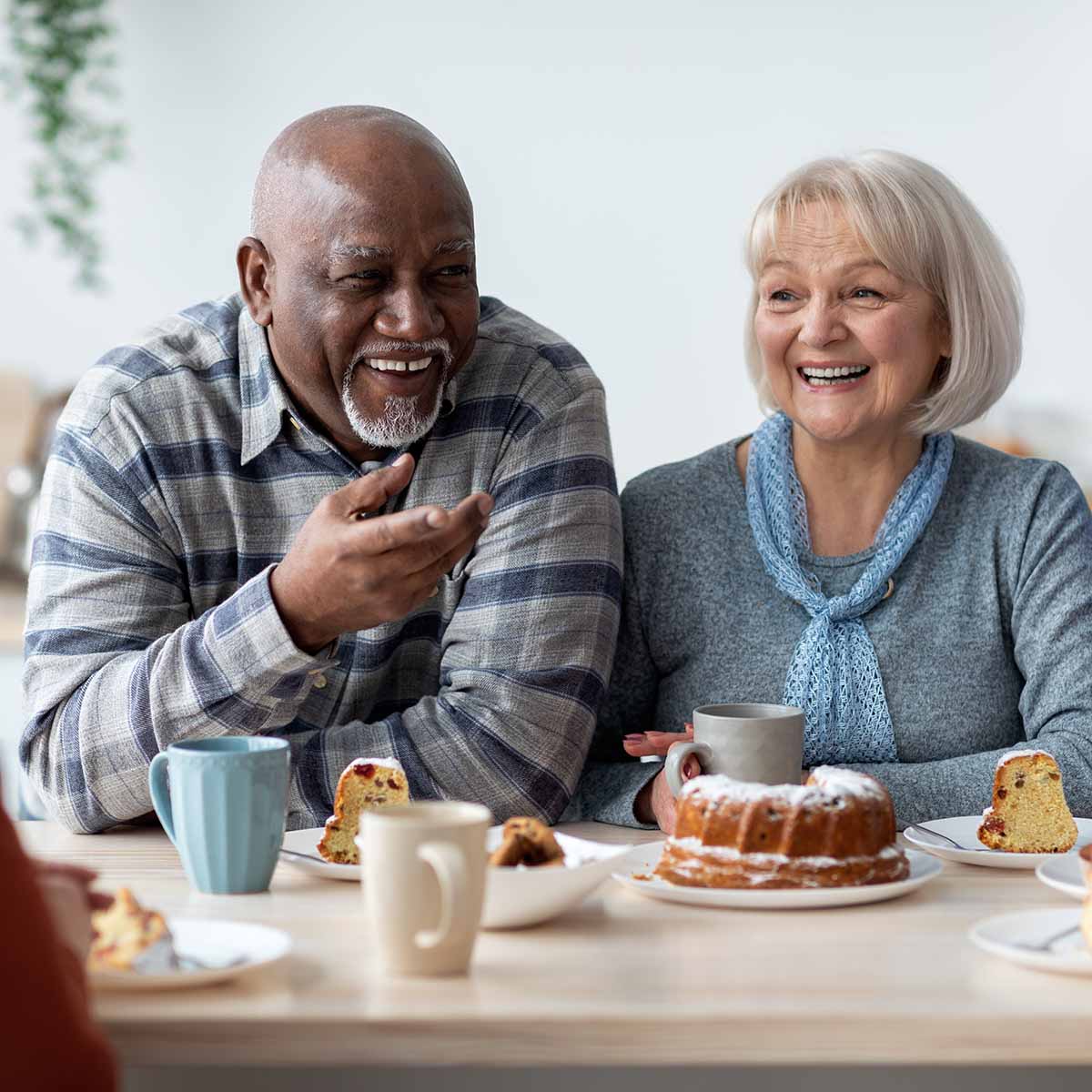 senior-friends-laugh-while-having-coffee-and-cake-together